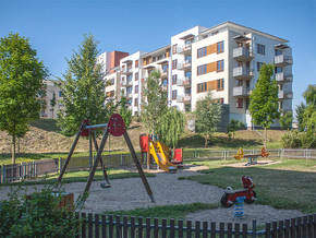 Dětské hřiště a v pozadí bytový dům Hortenzie a Gladiola